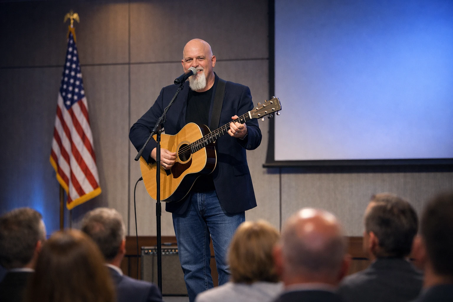 Conservative conference entertainment in Georgia with Phillip Rogers singing and playing acoustic guitar on a small conference stage with professional lighting and seated guests
